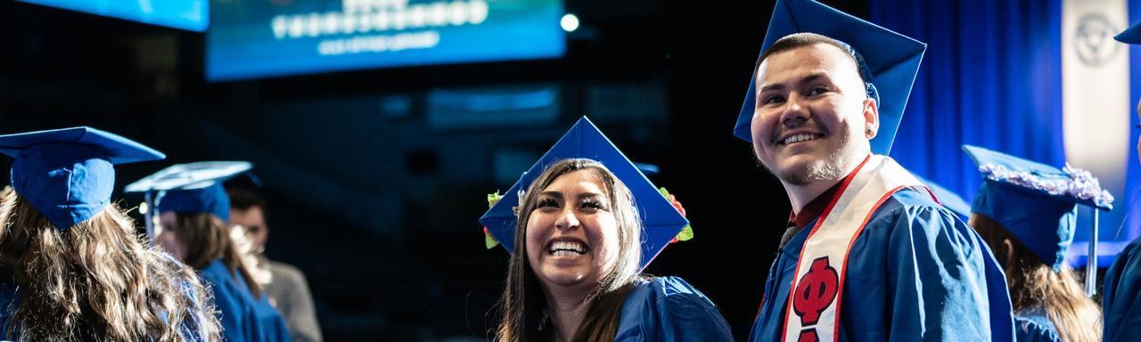 students standing at commencement in cap and gown